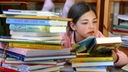 Kind liest inmitten eines Bücherstapels